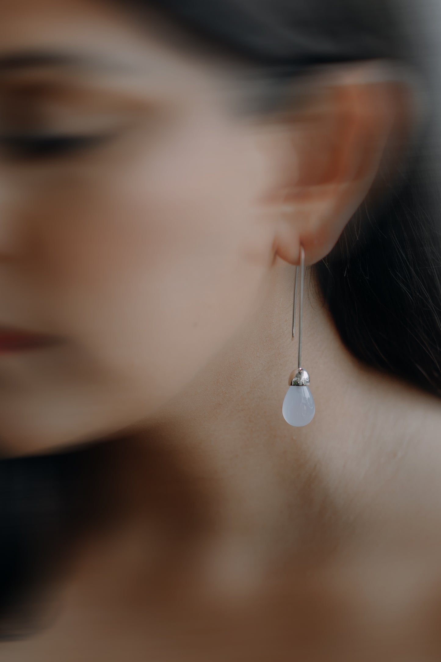 Model wearing Maancy Goutte sterling silver earring with chalcedony teardrop, showing elegant profile view of the contemporary jewelry design.