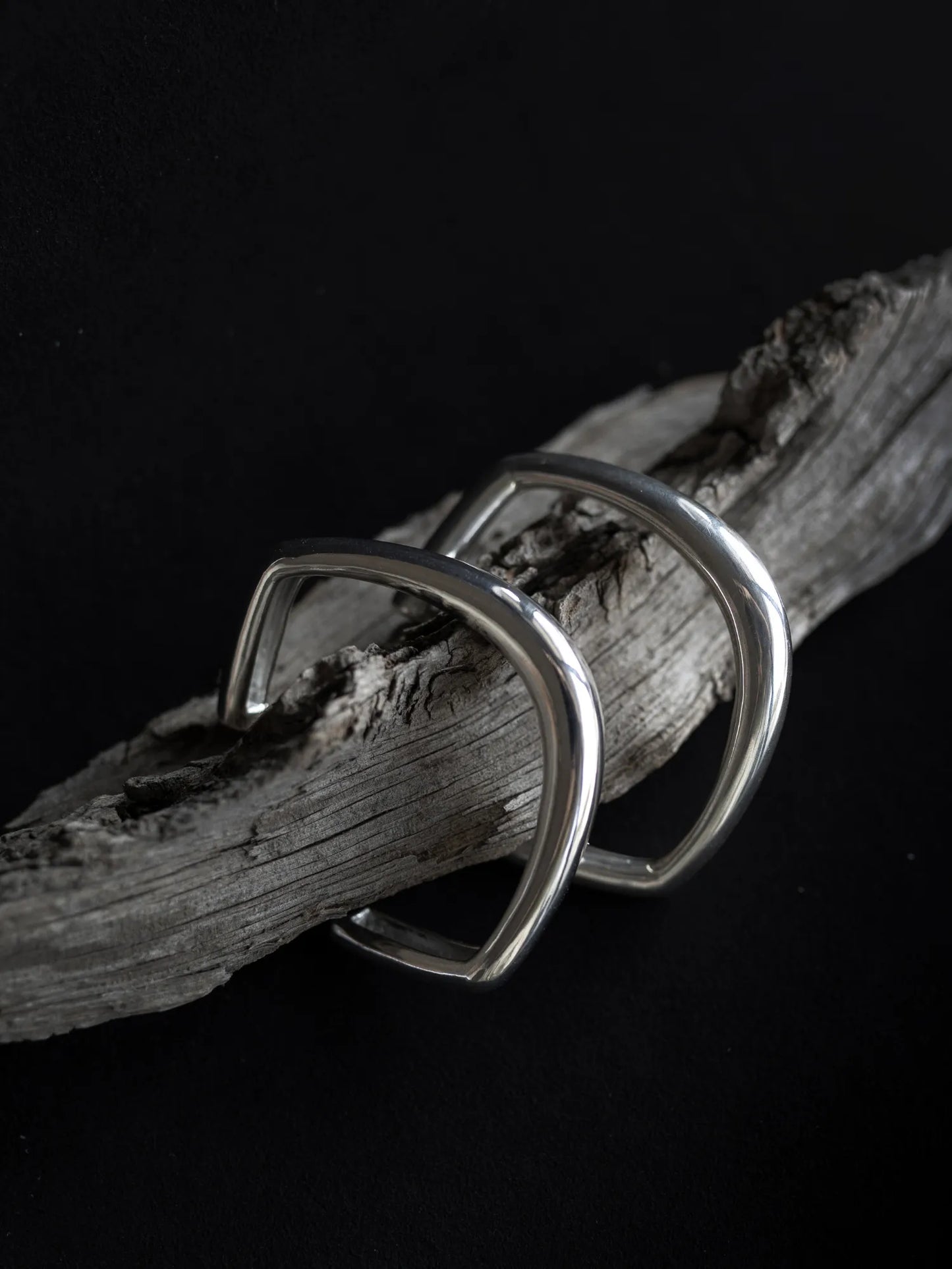 Maancy artisan made bangle pair in .925 sterling silver displayed on natural driftwood, highlighting the contrast between crafted metal and organic texture.