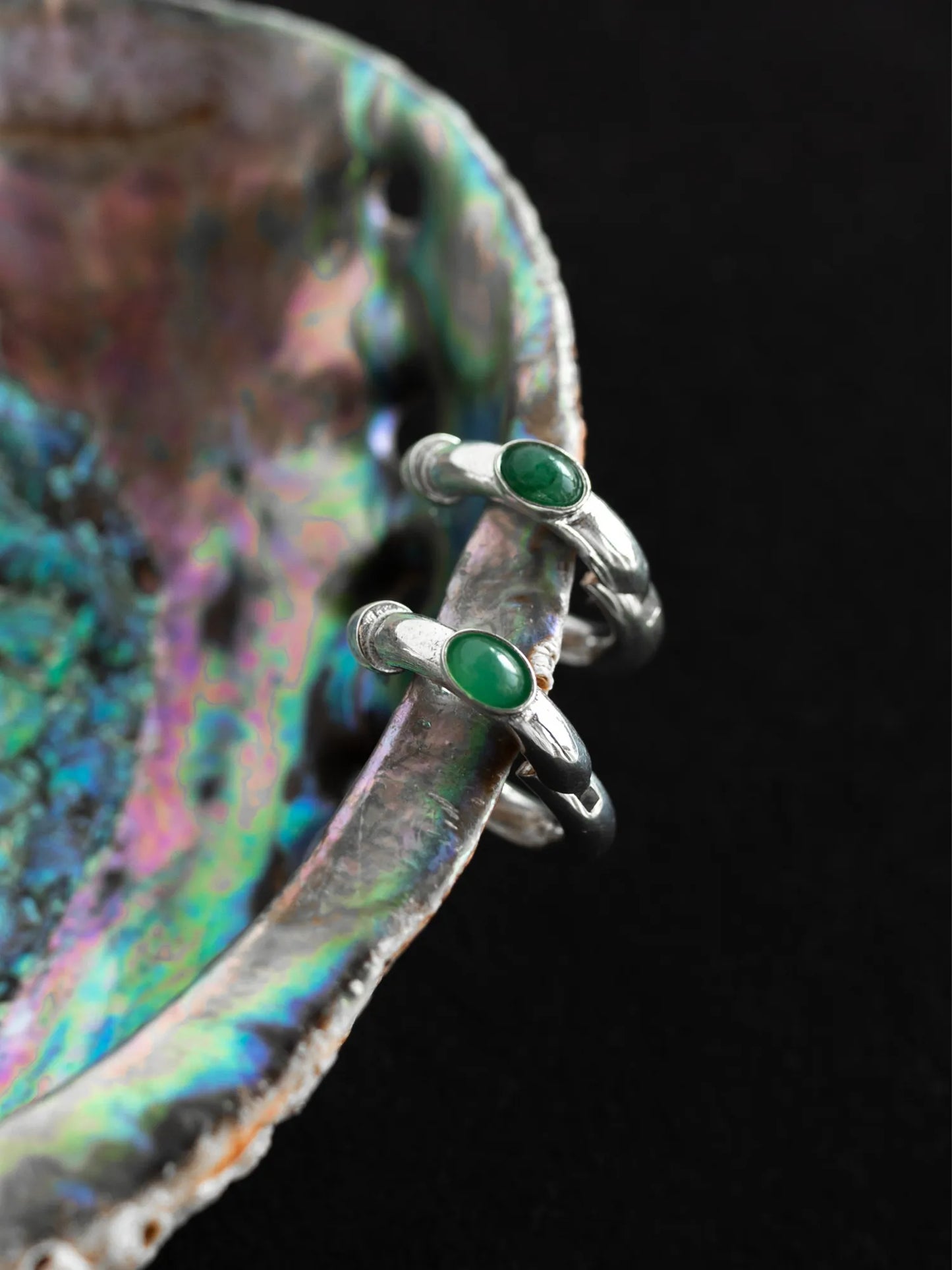 Maancy convertible silver hoop earrings with oval jade gemstones displayed on iridescent shell, highlighting the modular jewelry system.