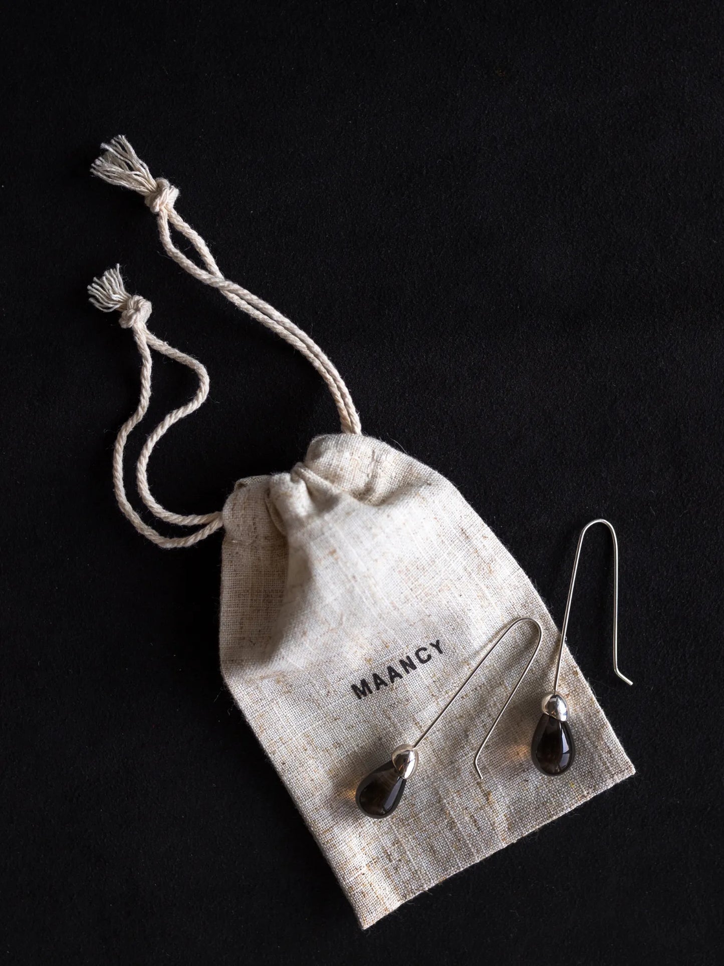 Maancy Goutte smoky quartz drop earrings with eco-friendly cotton packaging bag, highlighting sustainable jewelry presentation.