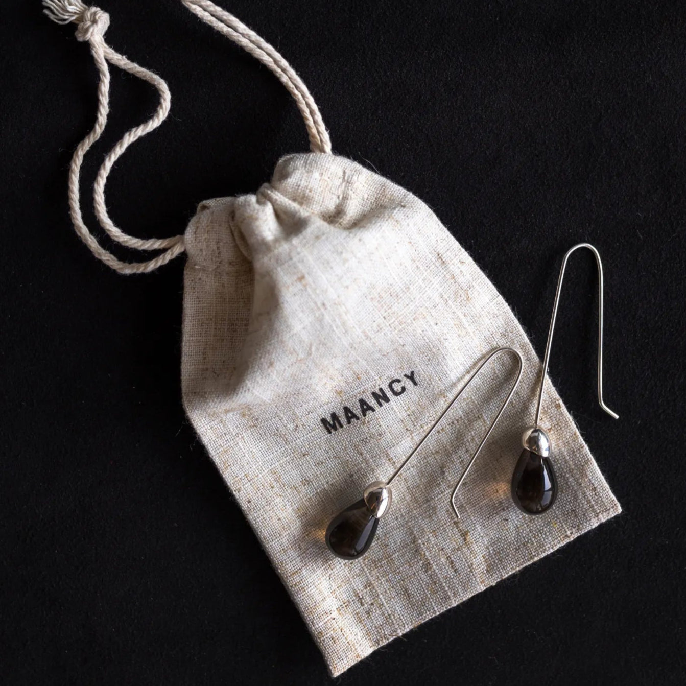 Maancy Goutte smoky quartz drop earrings with eco-friendly cotton packaging bag, highlighting sustainable jewelry presentation.
