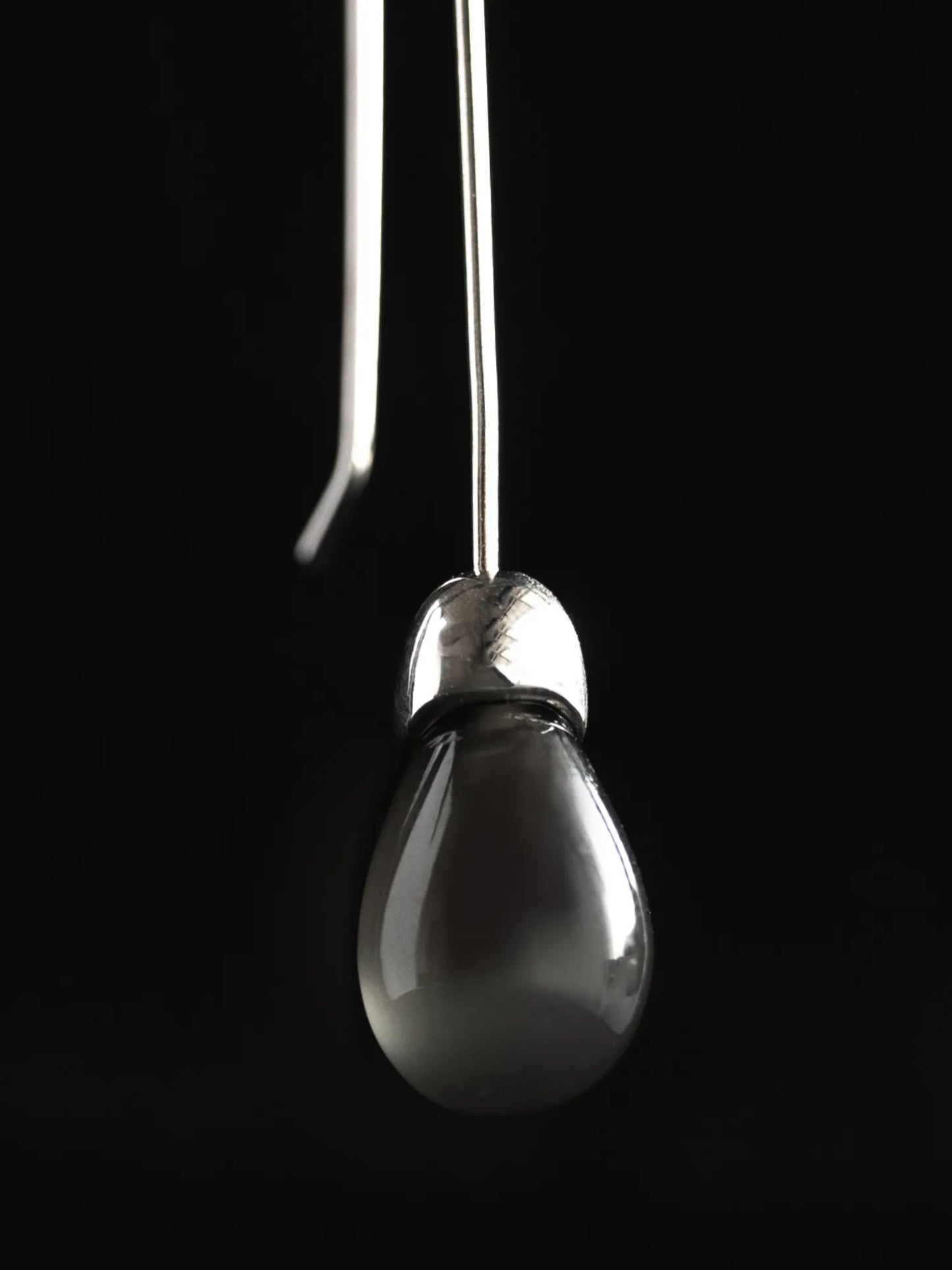 Close-up detail of Maancy Goutte earring showing the opalescent moonstone teardrop and handcrafted sterling silver cap design.