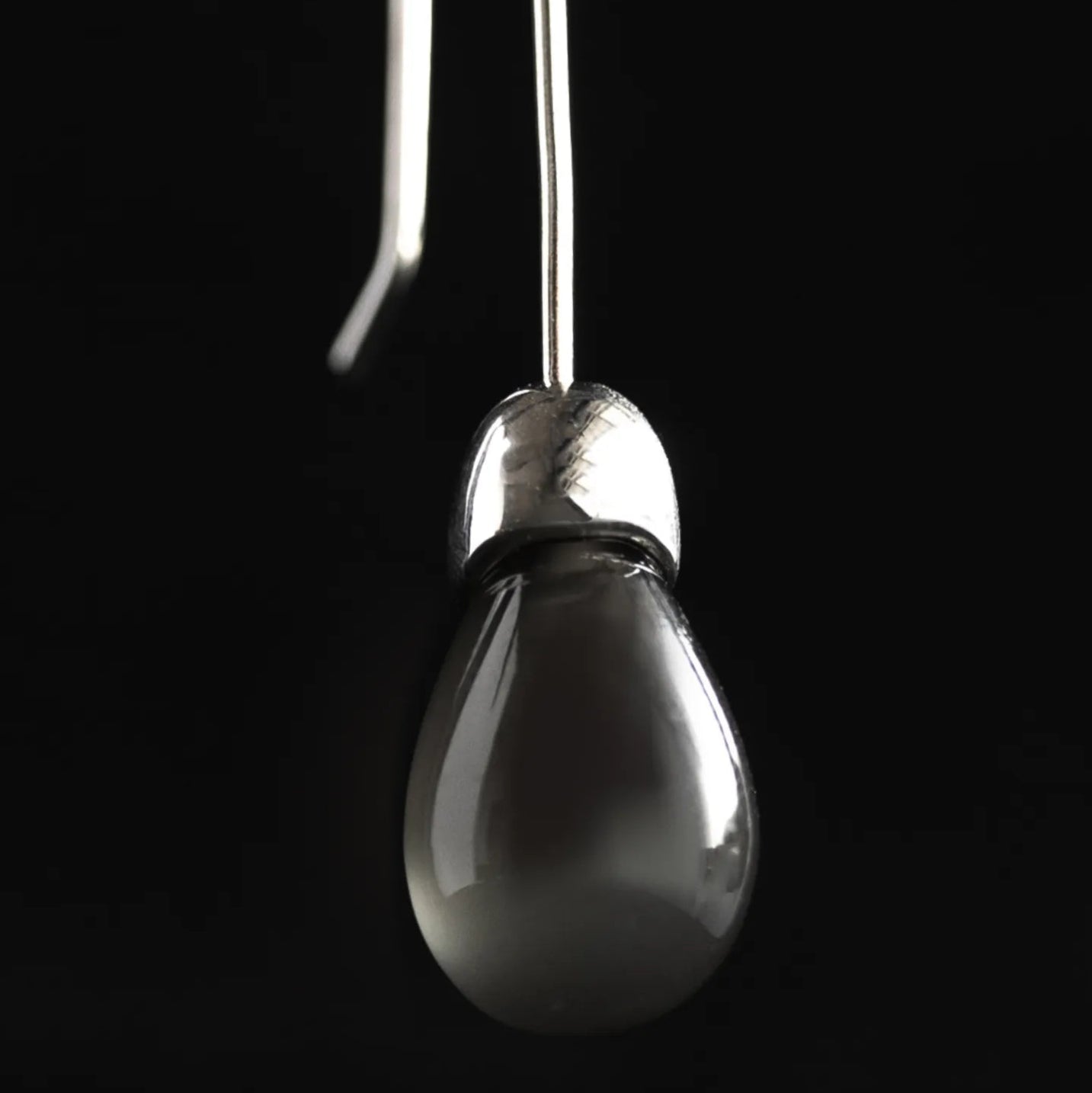 Close-up detail of Maancy Goutte earring showing the opalescent moonstone teardrop and handcrafted sterling silver cap design.