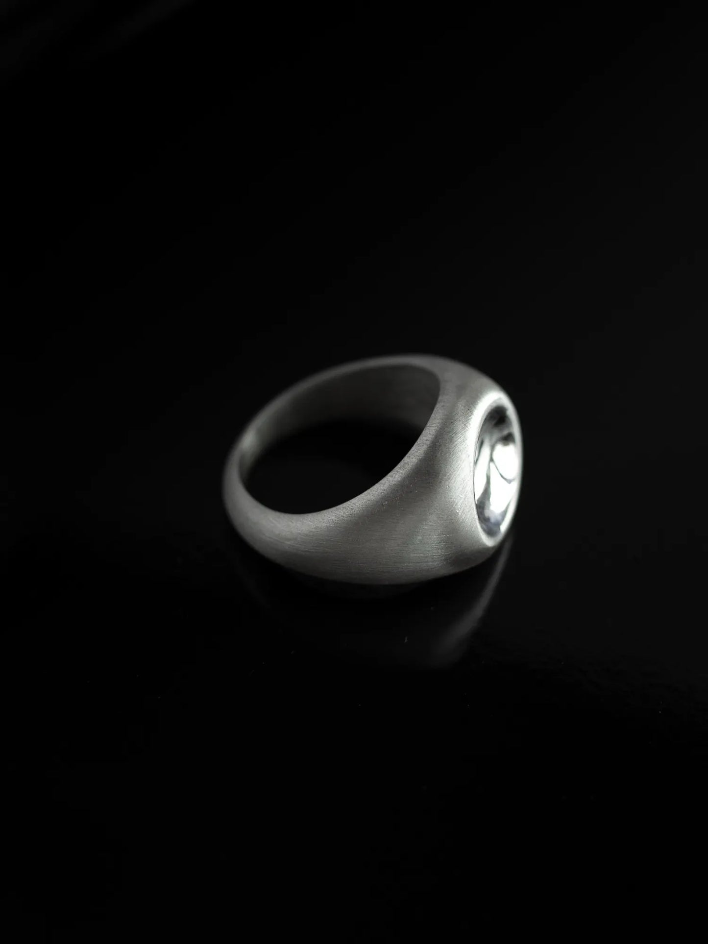 Maancy handcrafted silver dome ring with mirror-polished center against black background, showing the contrast between satin band and reflective dome.
