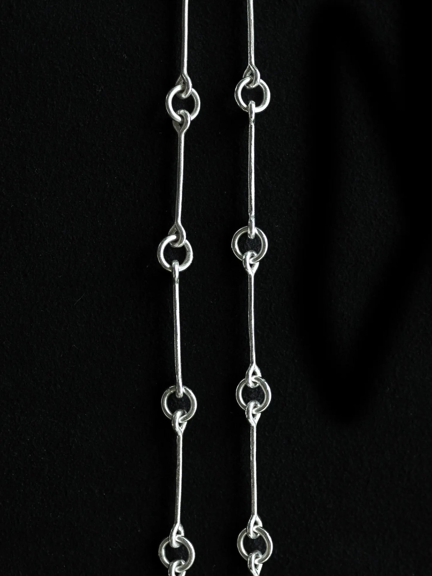 Maancy Infinity Chain Necklace detail showing handcrafted sterling silver link connections with bar and circular elements against black background.