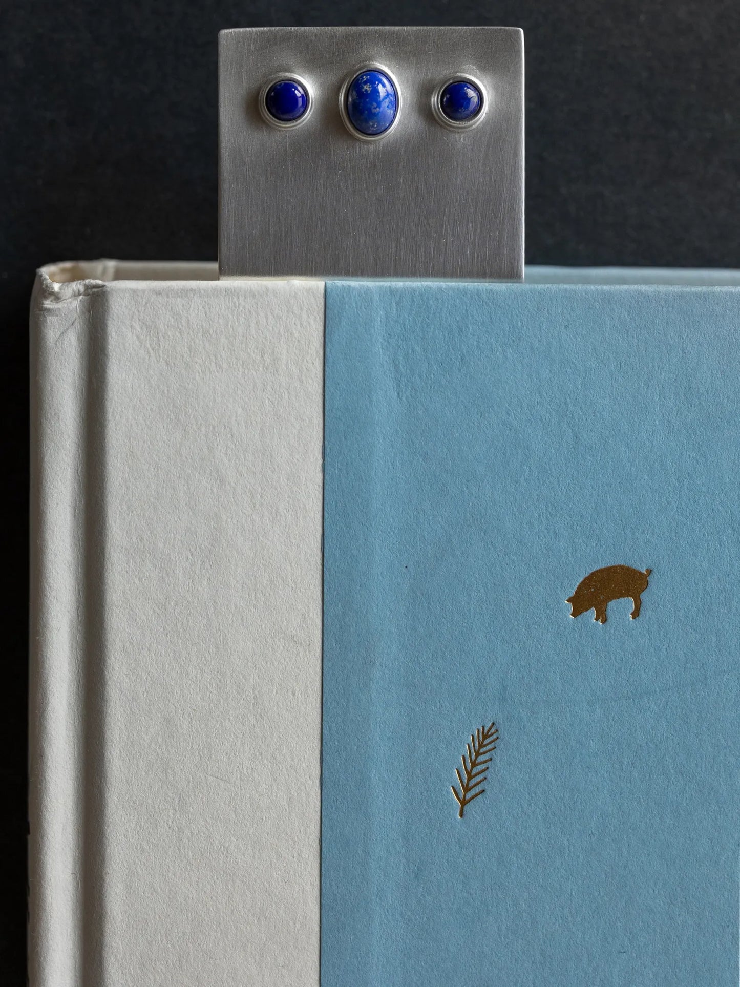 Maancy handcrafted silver bookmark with lapis lazuli stones styled with blue and white books, creating a coordinated aesthetic.
