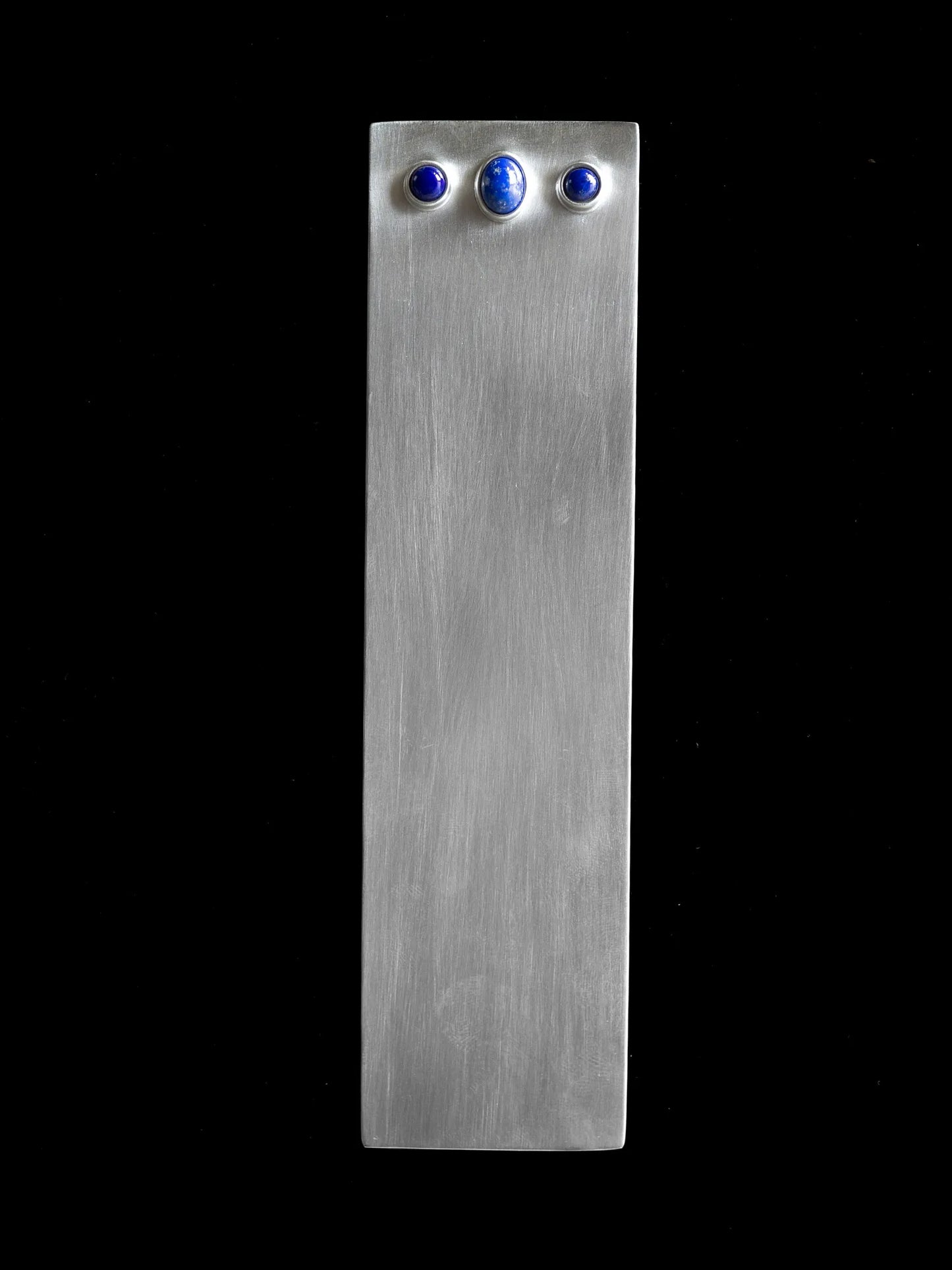 Full view of Maancy architectural sterling silver bookmark with three lapis lazuli cabochons set in brushed silver against black background.