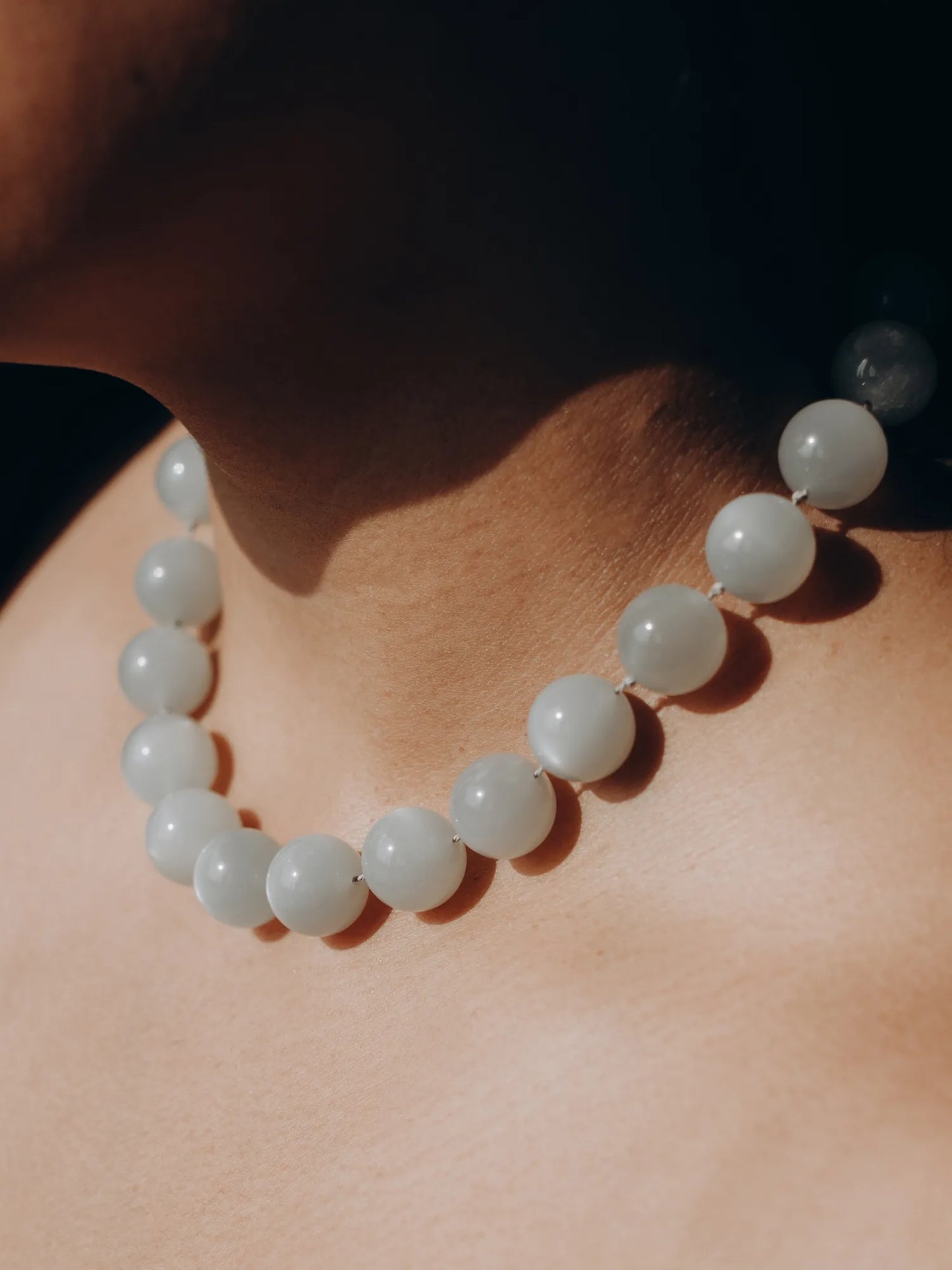 Model wearing Maancy moonstone Orb Collar necklace against neutral background, highlighting the opalescent glow of the spheres.
