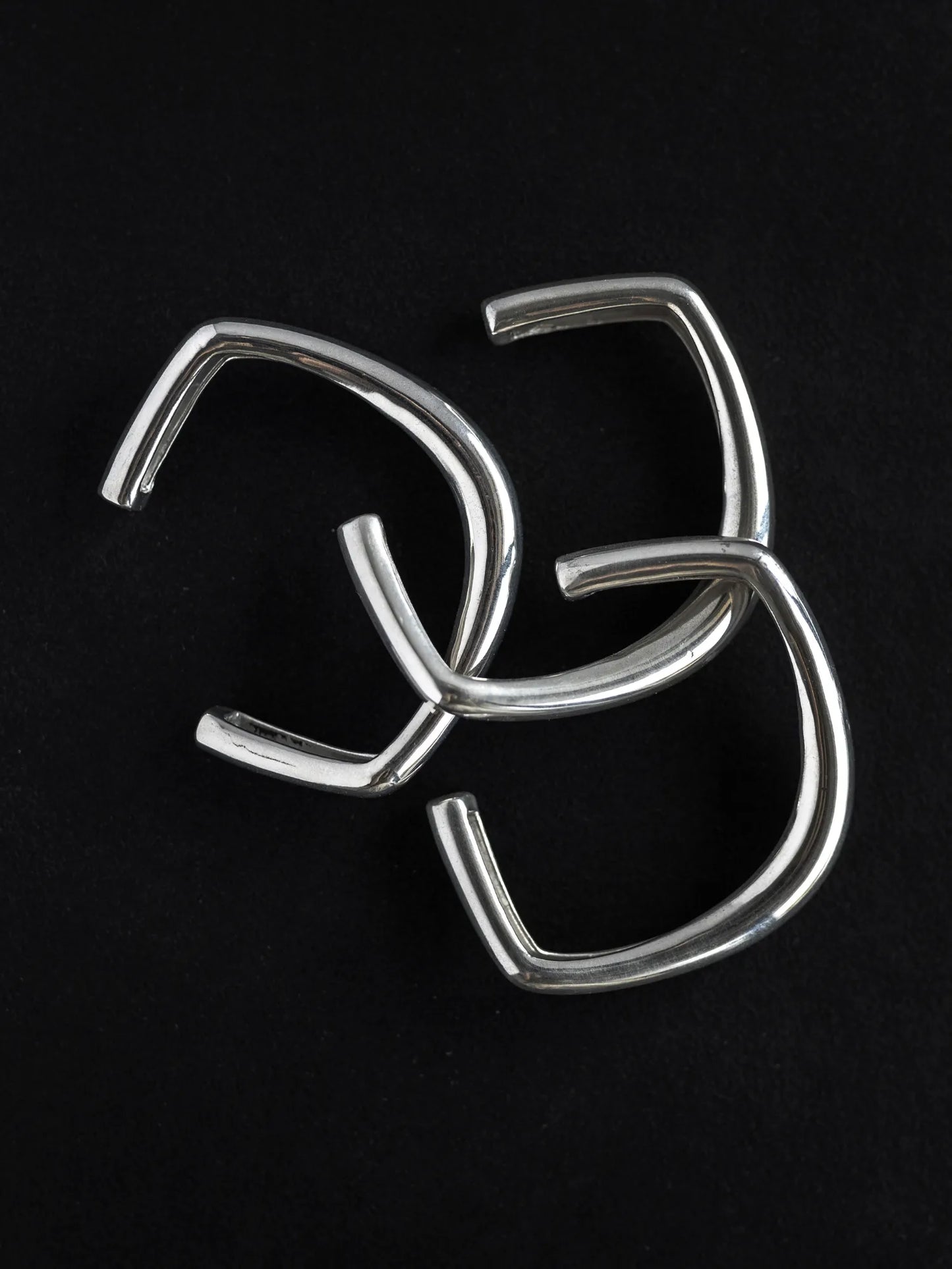 Maancy sculptural silver bangle trio with intersecting geometric planes, showcasing the contemporary design and clean angular aesthetic.