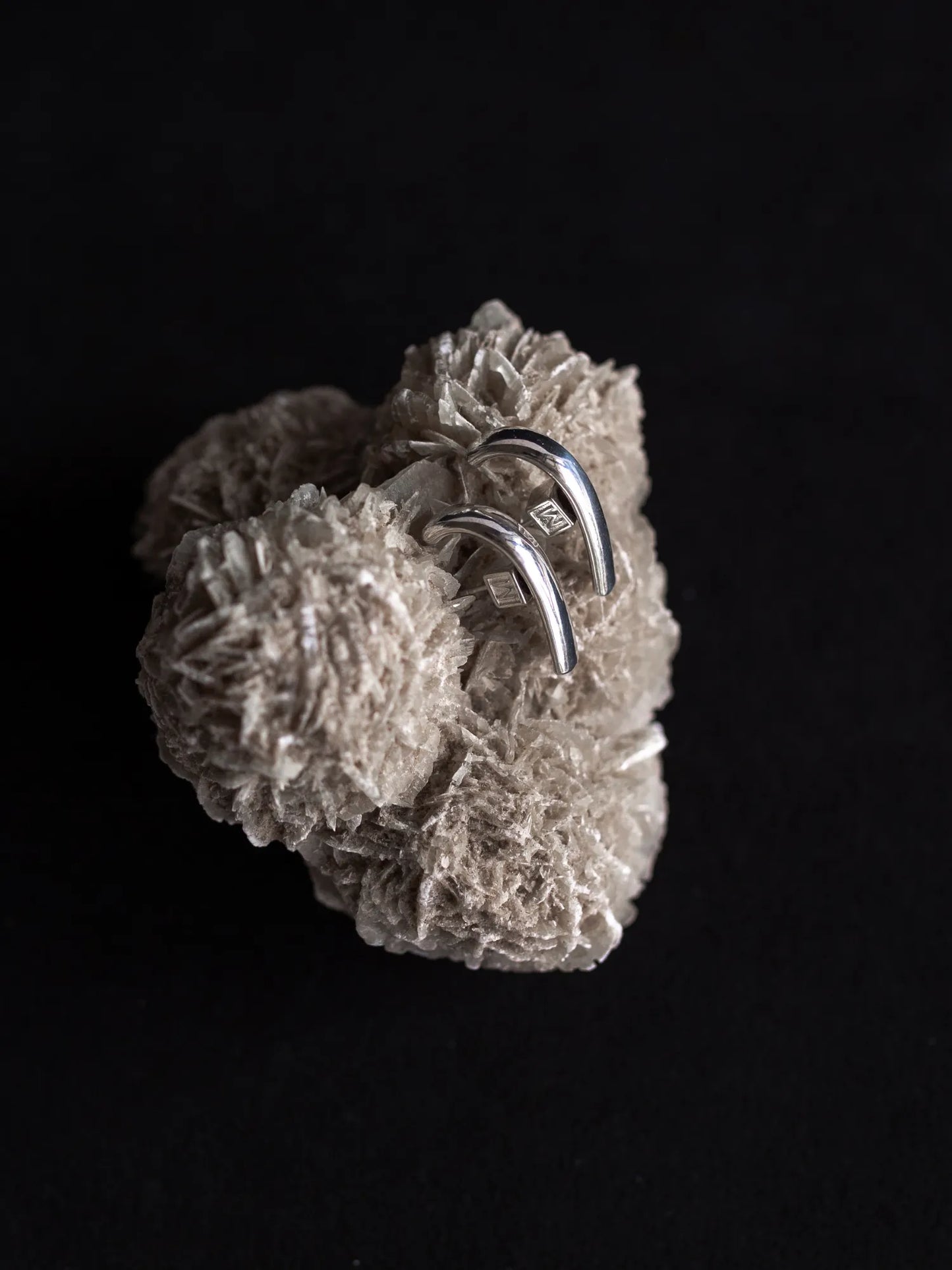 Maancy handcrafted sterling silver Half Moon cuff earrings displayed on white crystal formation, highlighting contemporary minimalist jewelry design.