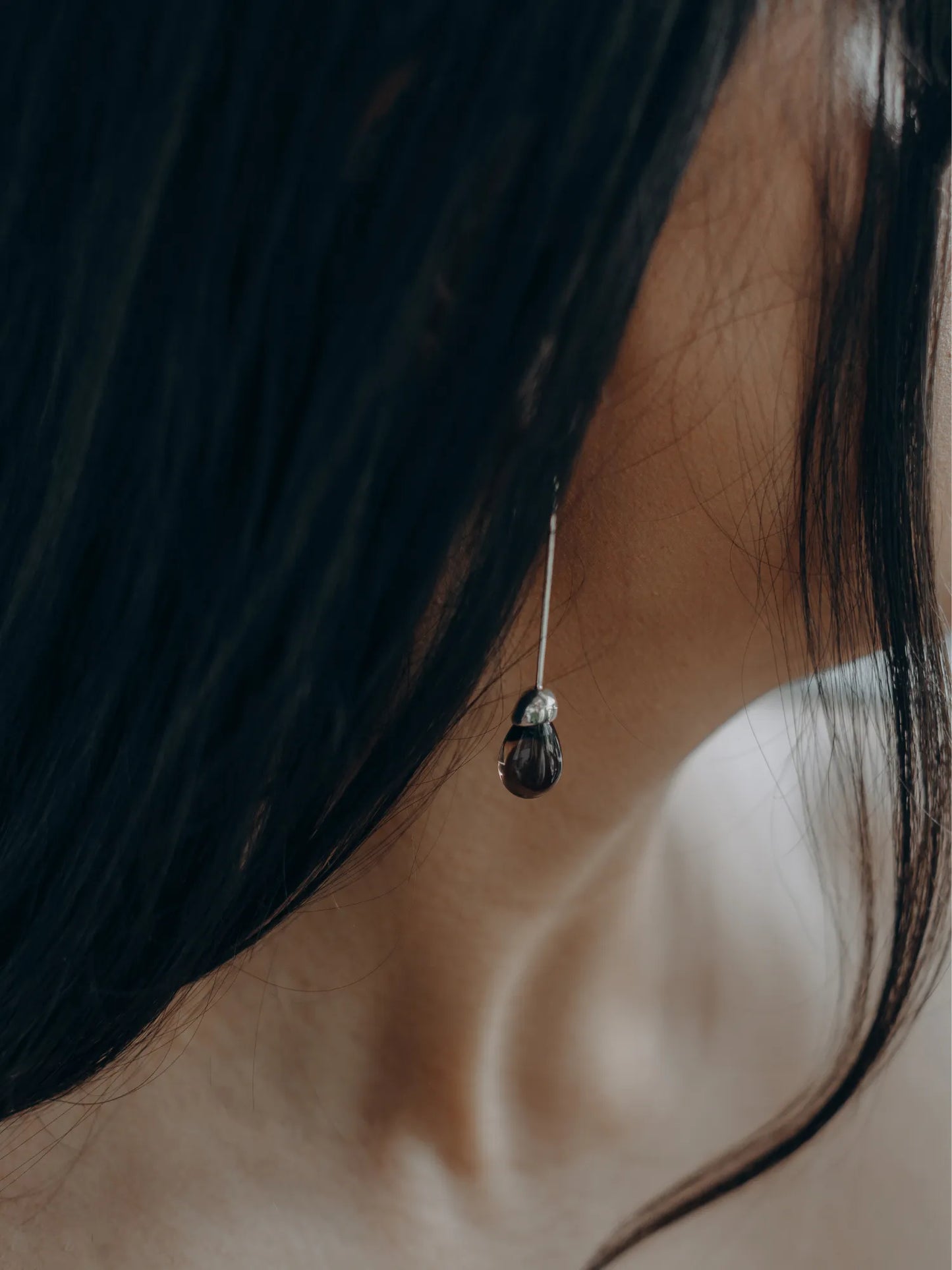 Profile view of model wearing Maancy handcrafted silver Goutte earring with smoky quartz teardrop gemstone.