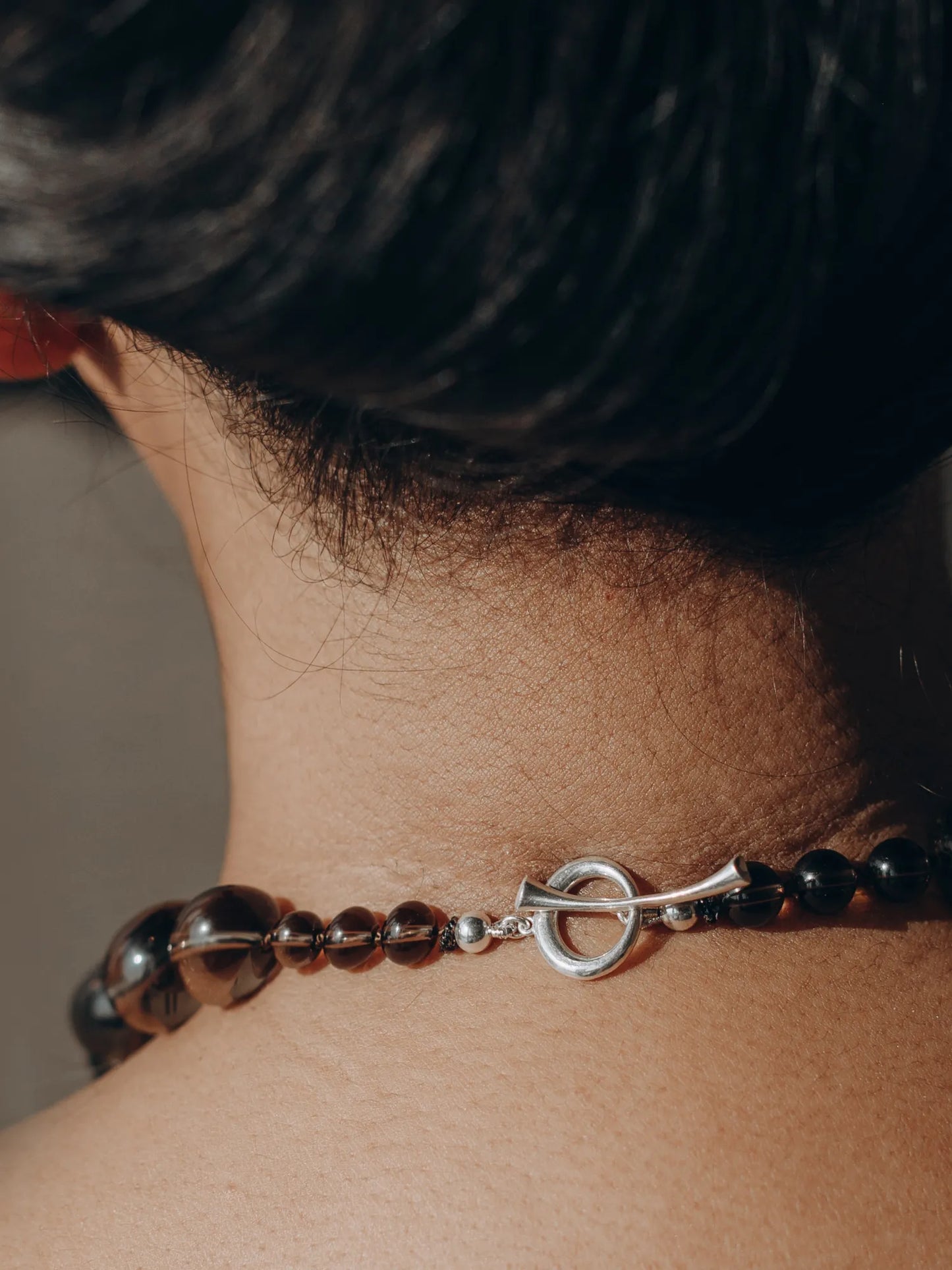 Detail of Maancy smoky quartz Orb Collar necklace's sterling silver toggle clasp at the nape, showcasing craftsmanship.