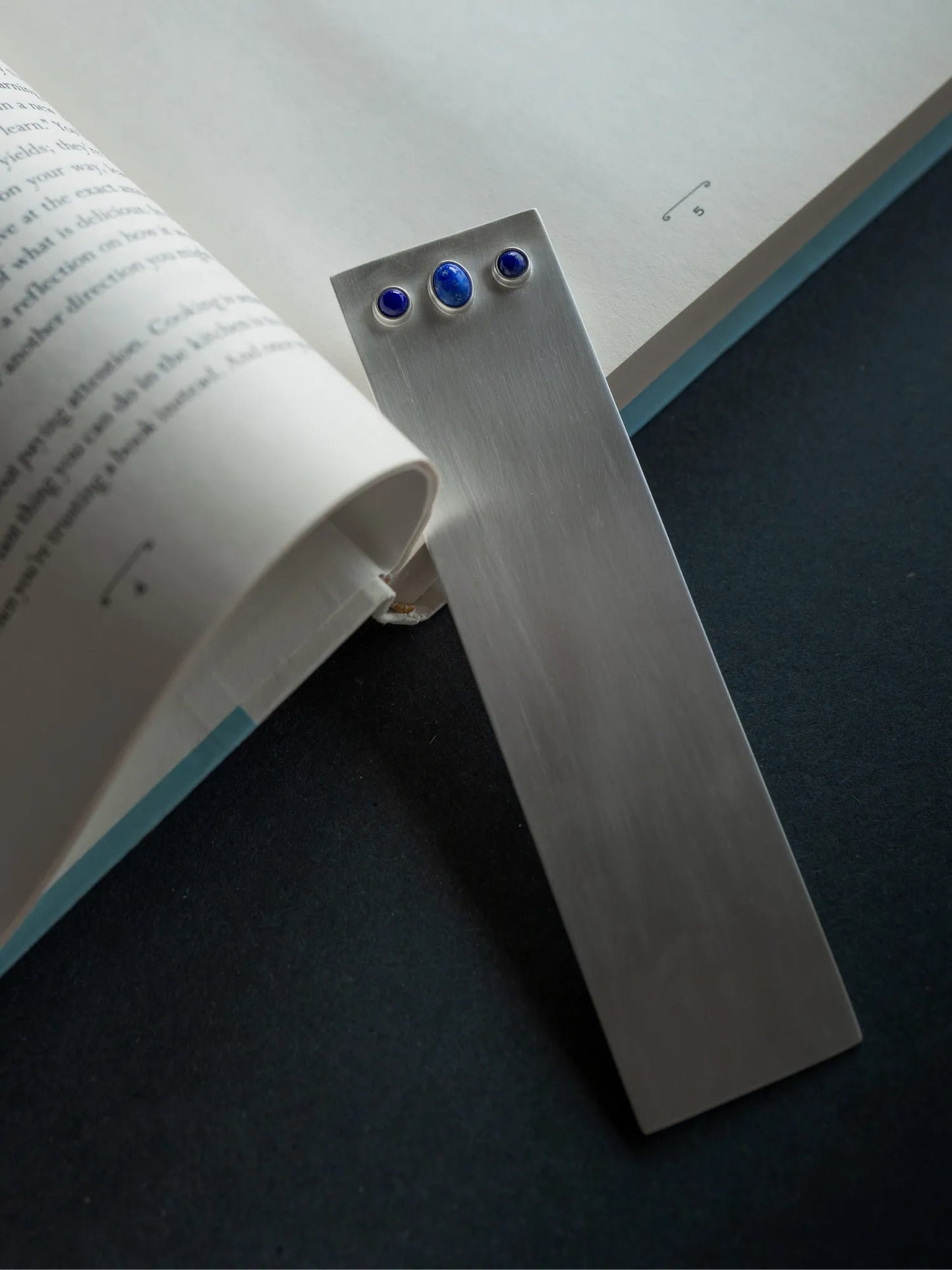 Maancy sterling silver bookmark with blue lapis stones in use marking pages in an open book, showing practical functionality