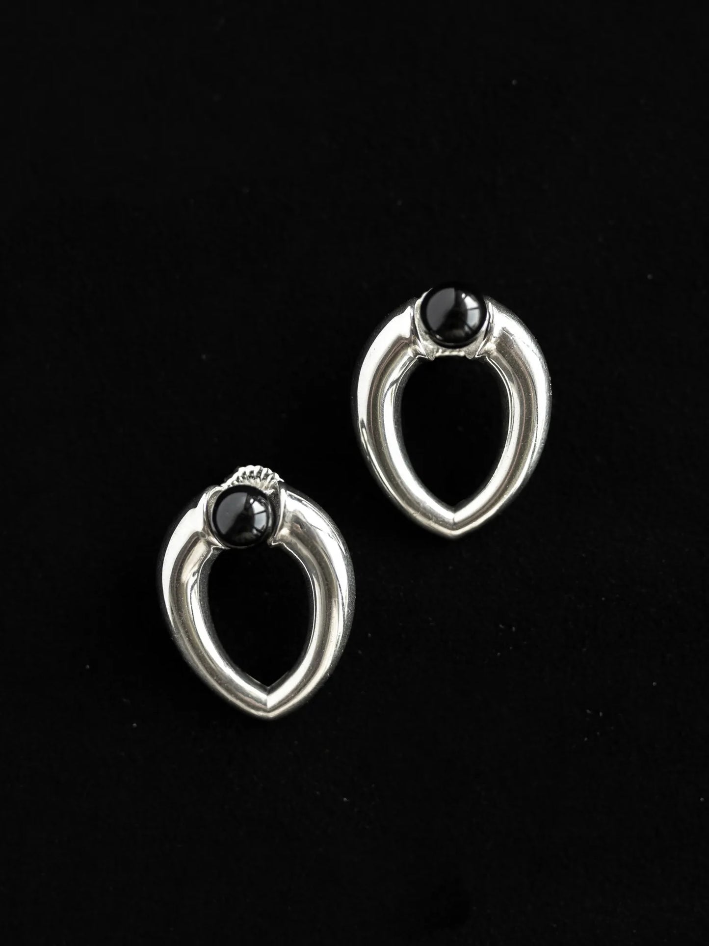 Maancy handcrafted sterling silver teardrop earrings with black onyx spheres, displaying contemporary sculptural form on black background.