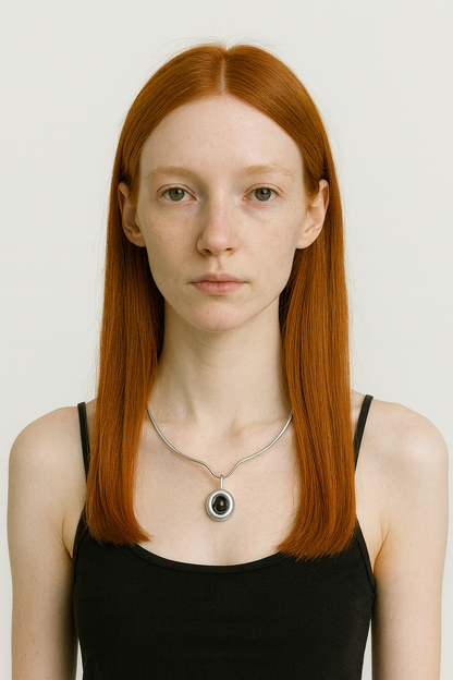 Woman with red hair wearing a black tank top and silver necklace with carnelian pendant on a white background 