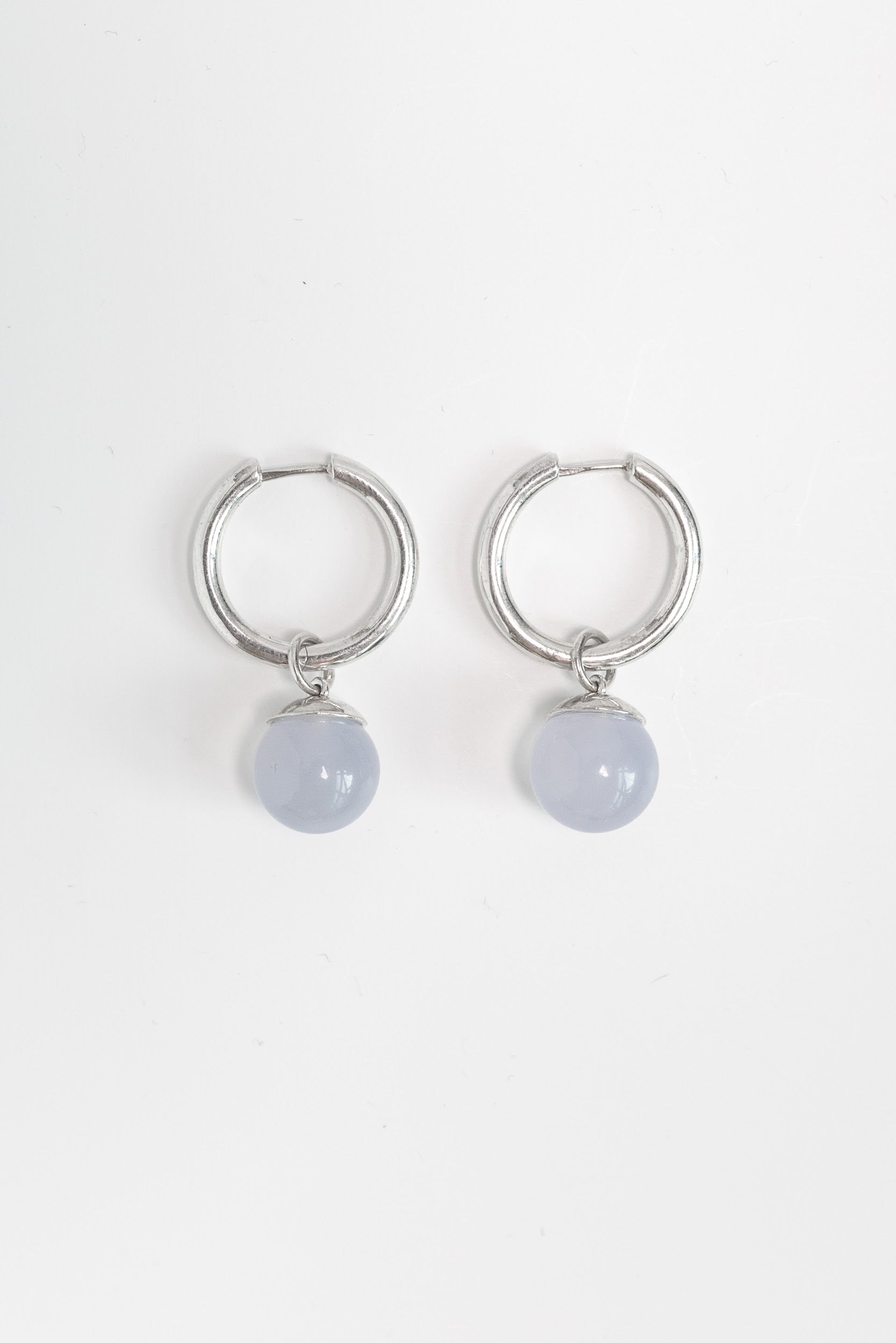 Silver hoop earrings with blue chalcedony stones with charms shown with white background 