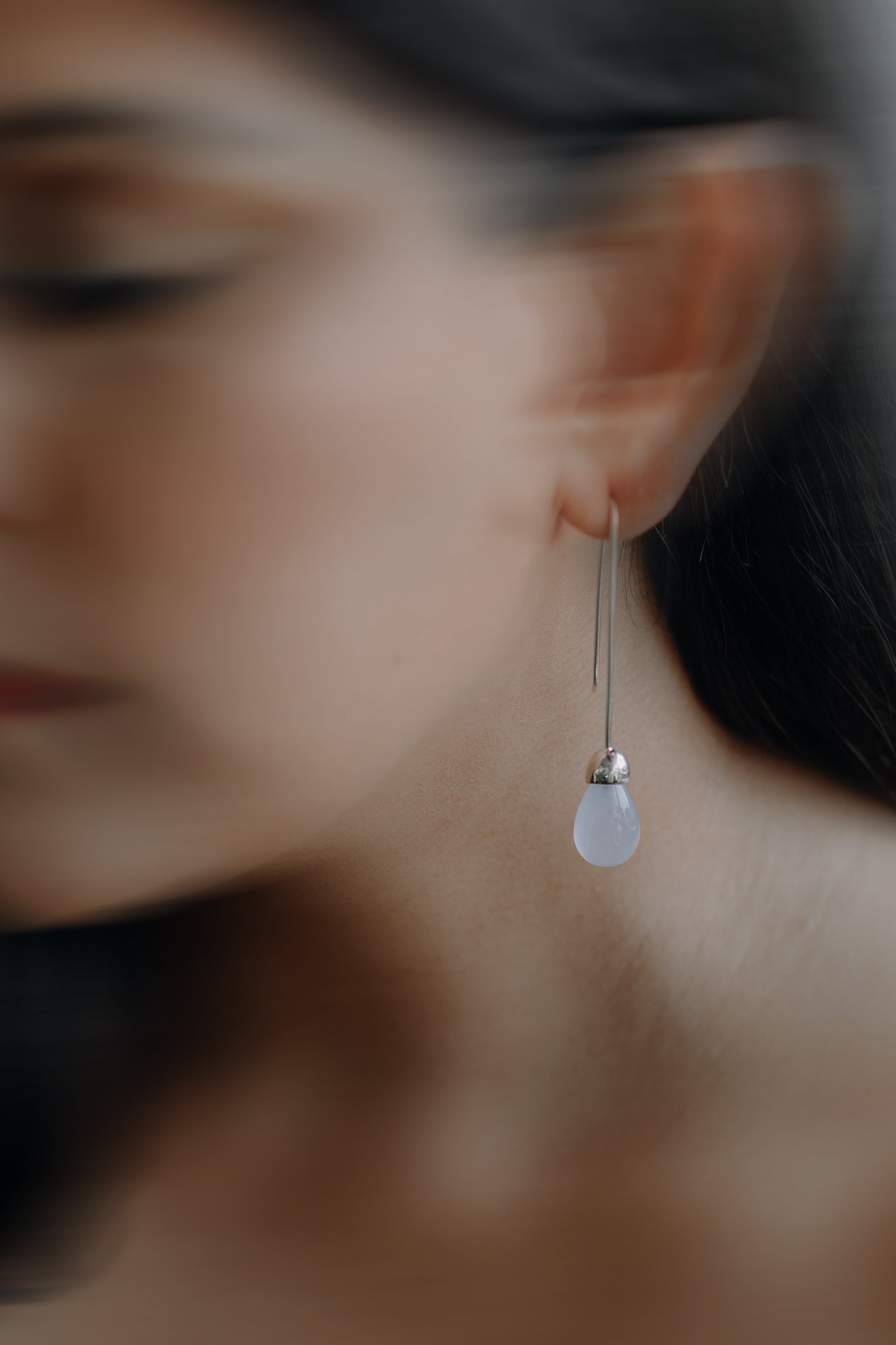 Model wearing Maancy Goutte sterling silver earring with chalcedony teardrop, showing elegant profile view of the contemporary jewelry design.