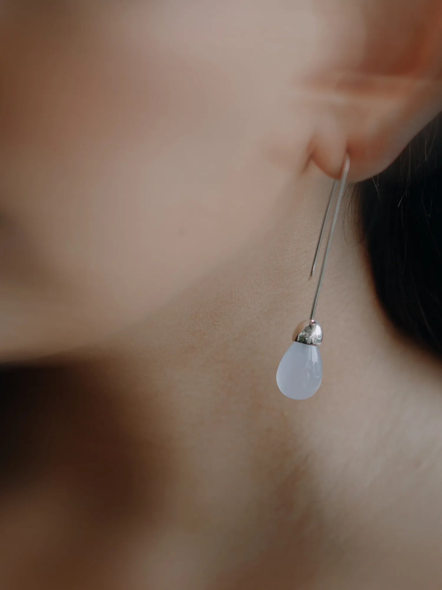 Model wearing Maancy Goutte sterling silver earring with chalcedony teardrop, showing elegant profile view of the contemporary jewelry design.