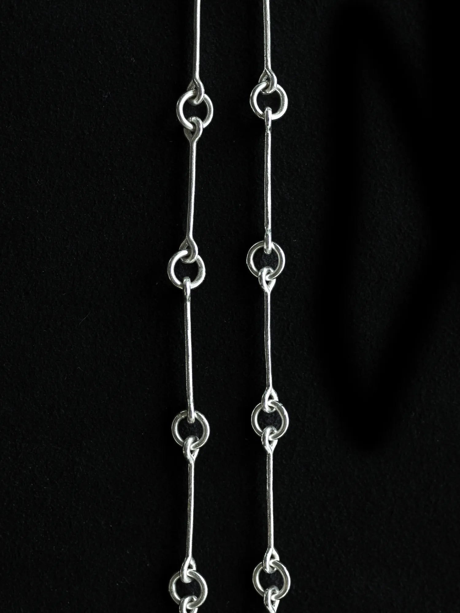 Maancy Infinity Chain Necklace detail showing handcrafted sterling silver link connections with bar and circular elements against black background.