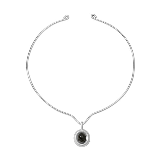 Silver necklace with a black onyx pendant on a white background. 